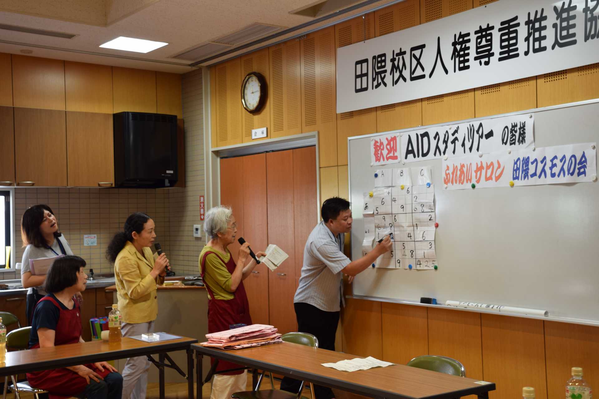 「田隈コスモスの会」を訪れ、介護予防のため数独ゲームに加わったタイからの参加者（写真右）