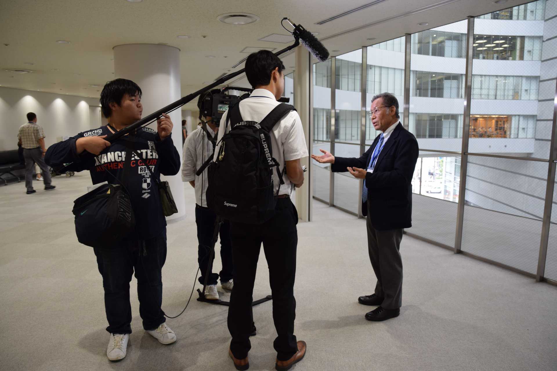 シンポジウムの会場で、地元テレビのインタビューに応じる大野修一・笹川平和財団理事長。