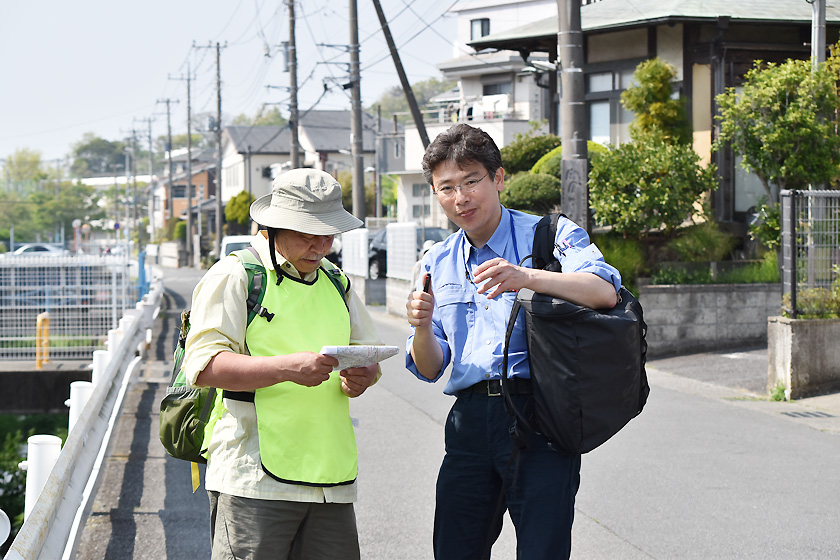 （写真）鎌倉市内の川を調査員とともに歩く塩入研究員